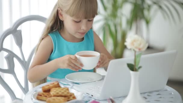 Linda niña sentada en la mesa con portátil — Vídeos de Stock