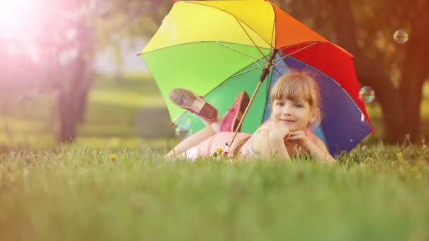 Kinderen liegen met paraplu en glimlachen. Lens flare en zonlicht. — Stockvideo