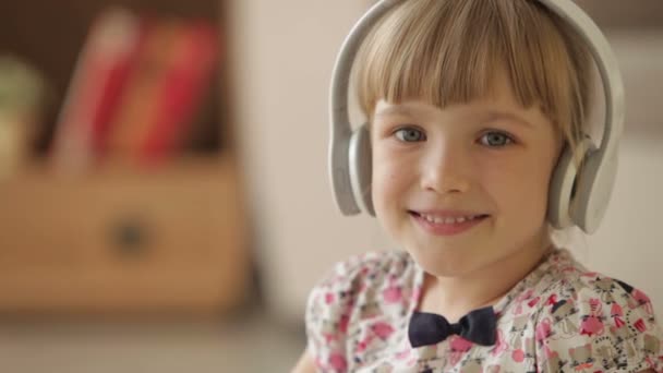 Alegre niña en auriculares sonriendo — Vídeos de Stock