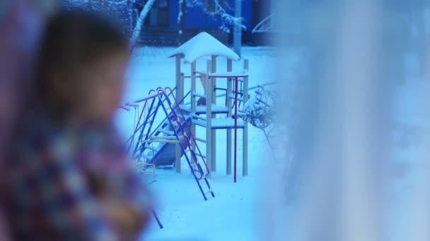 Sad child girl looking out the window — Stock Video