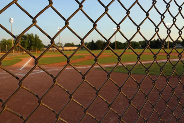 Eine Weitwinkelaufnahme Eines Baseballfeldes Die Der Abenddämmerung Durch Einen Maschendrahtzaun — Stockfoto