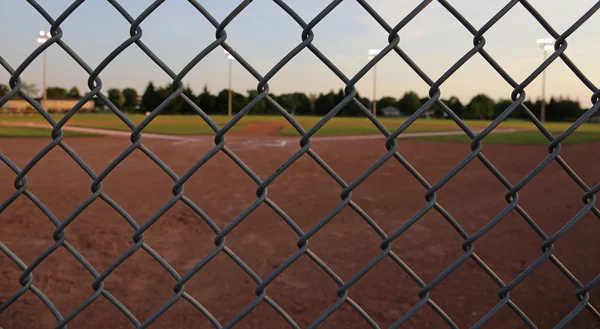 一个棒球场的广角拍摄在黄昏时通过链路栅栏拍摄 — 图库照片