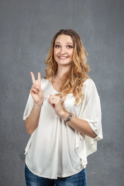 Mujer joven mostrando V para el gesto de victoria — Foto de Stock