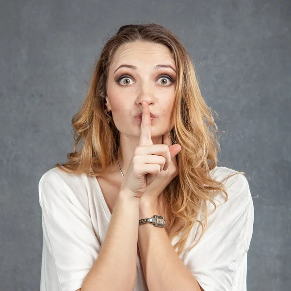 Attractive young woman with finger on lips — Stock Photo, Image