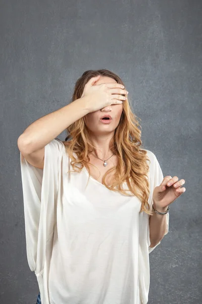 Young woman covering eyes with hand in studio — Stock Photo, Image