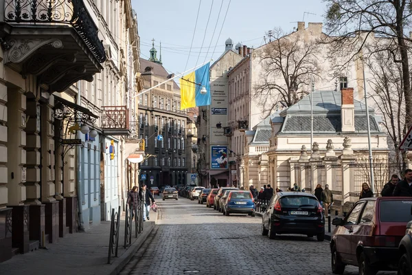 Львов, Украина - 22 февраля 2015 г. Узкая улица Львова с большим украинским флагом — стоковое фото