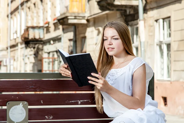 Chica tendida en el banco y libro de lectura —  Fotos de Stock