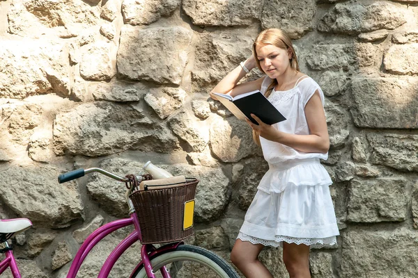 Vrouwen lezen van boek tegen oude stenen muur — Stockfoto