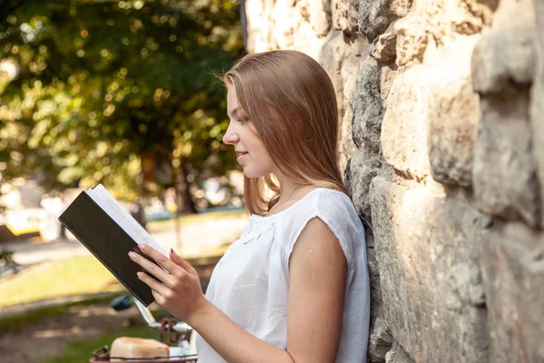 Vrouwen lezen van boek tegen oude stenen muur — Stockfoto