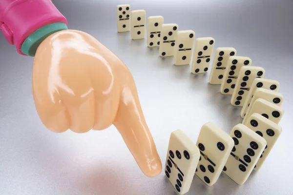 Plastikhand und Reihe von Dominosteinen — Stockfoto
