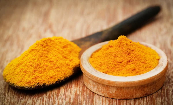 Gemalen tumeric in een lepel en kom — Stockfoto