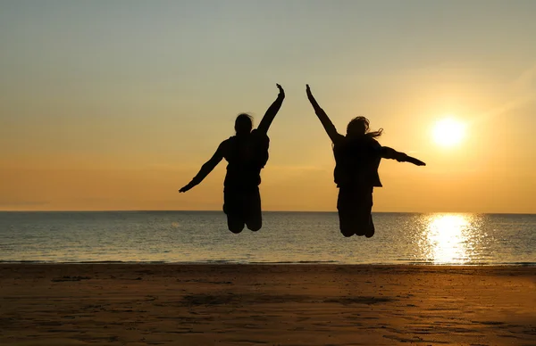 Two young girls jumping at beach — Stock Photo, Image