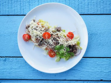 Mavi ahşap arka planda et salatası