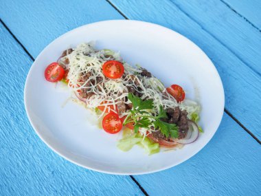 Mavi ahşap arka planda et salatası