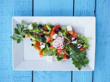 Mavi ahşap arka planda salatalık ve domates salatası.