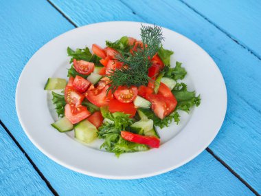 Mavi ahşap arka planda salatalık ve domates salatası.