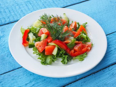 Mavi ahşap arka planda salatalık ve domates salatası.