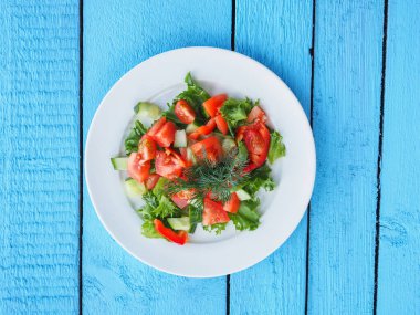 Mavi ahşap arka planda salatalık ve domates salatası.