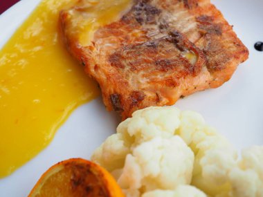 Kırmızı zemin üzerinde folyoda pişmiş somon balığı.