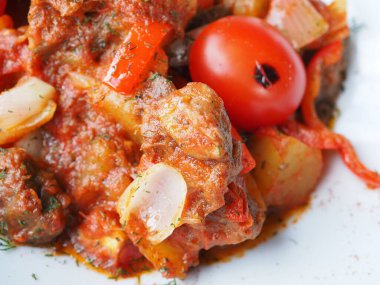 Kırmızı arka planda domatesli biftek ve otlar.