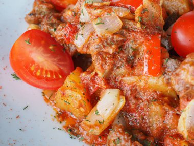 Kırmızı arka planda domatesli biftek ve otlar.