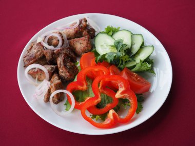 Kırmızı arka planda domatesli biftek ve otlar.