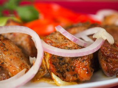 Kırmızı arka planda domatesli biftek ve otlar.