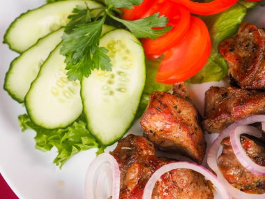 Kırmızı arka planda domatesli biftek ve otlar.