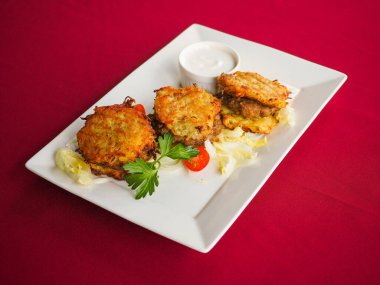 Kırmızı arka planda domatesli biftek ve otlar.