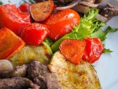 Kırmızı arka planda domatesli biftek ve otlar.