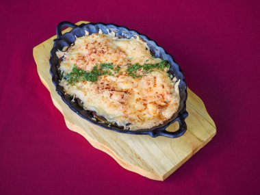 Kırmızı arka planda domatesli biftek ve otlar.