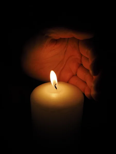 Svíčka a ruce na černém pozadí — Stock fotografie