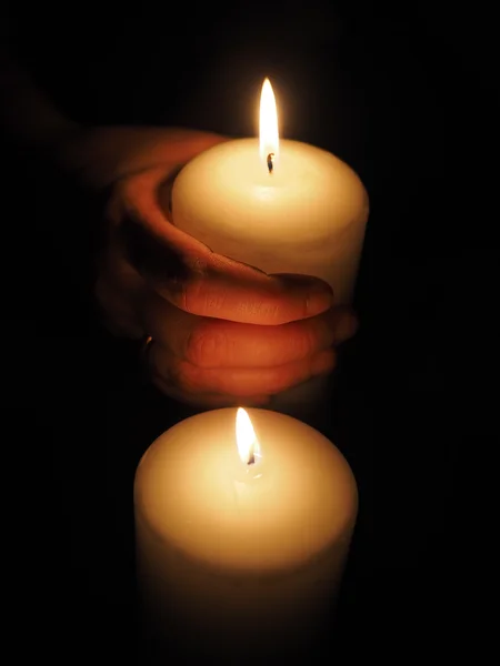 Candle and hands on a black background — Stock Photo, Image