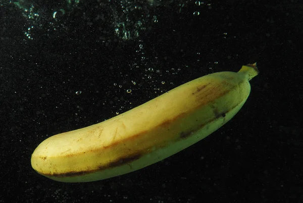 Banaan in water met de bubbels op een donkere achtergrond — Stockfoto