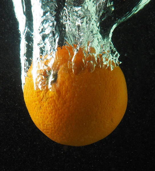 Laranja na água com bolhas em um fundo escuro — Fotografia de Stock