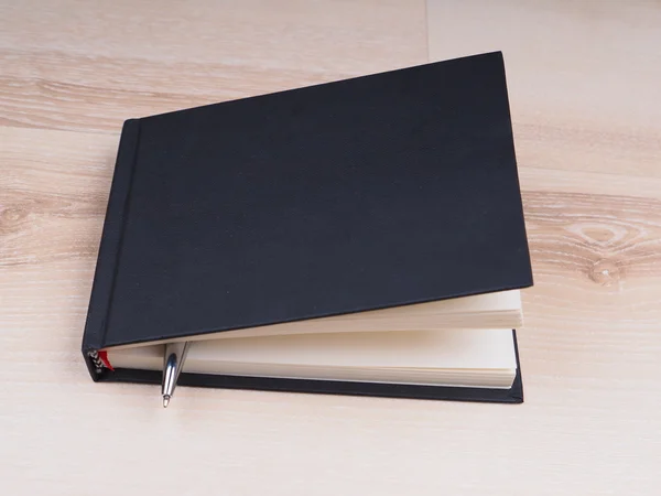 Notebook nero con penna su sfondo di legno — Foto Stock