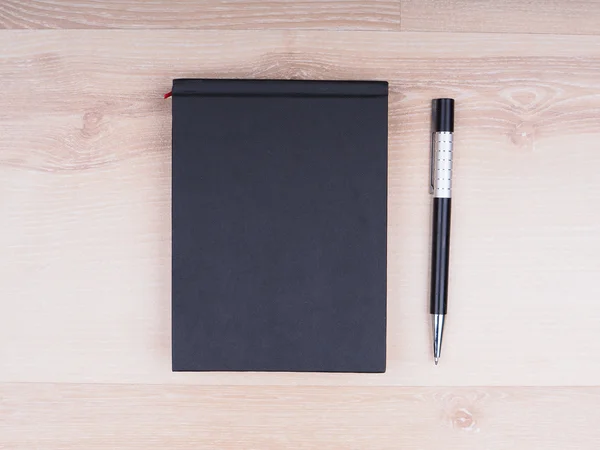 Zwart Zakboekje met een pen op een houten achtergrond — Stockfoto