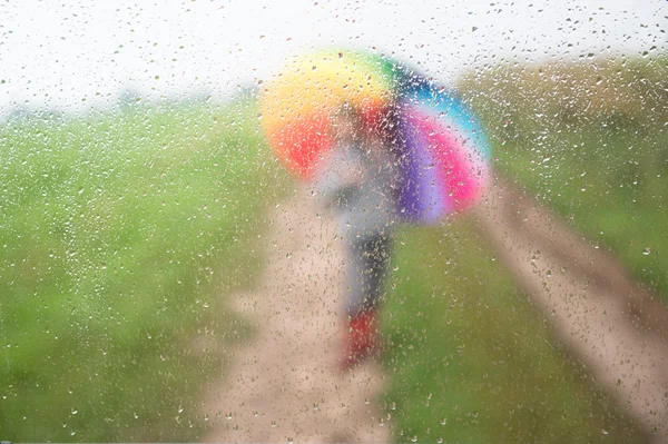 Bir şemsiye yağmur damla ile camın çocukla