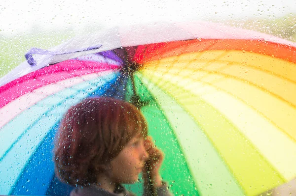 Bir şemsiye yağmur damla ile camın çocukla