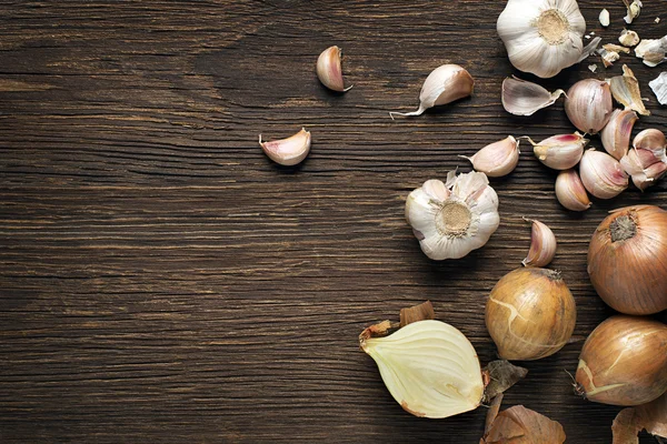 Knoblauch und Zwiebeln auf Holztisch — Stockfoto