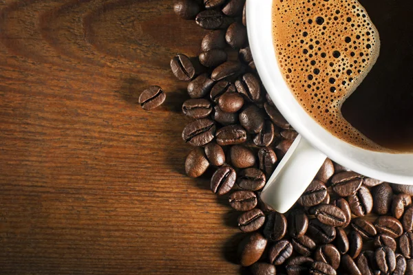 Taza de café y frijoles en mesa de madera — Foto de Stock