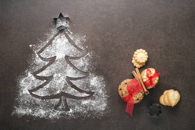 Karanlık bir masa üzerindeki undan yapılmış Noel ağacı, mutfak aletleri ve kurabiyeler. tatil, kutlama ve yemek pişirme konsepti. Yeni yıl ve Noel kartpostalı