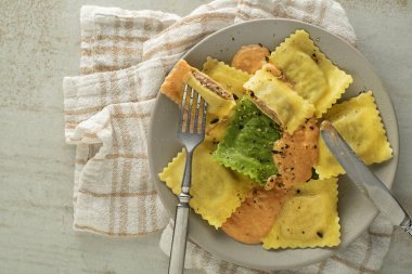 Ravioli makarnası, sebze sosuyla servis edilir. İçinde et, peynir ve sebze bulunan küçük makarna zarfları.