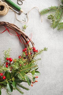 Doğal ladin dalları, ardıç ve kutsal kırmızı meyvelerden Noel çelengi yapmak. Evde Noel çelengi için süslemeler