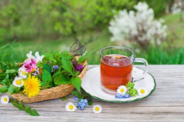 Ev bahçesindeki ahşap arka planda bir fincan sağlıklı bitki çayı..
