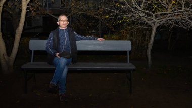 Kişi başlığını çıkardı ve ellerinin arasına aldı, gece meydanında rahatça oturdu, etrafta kimse yoktu, sakin ve serin sonbahar atmosferi hissedildi.