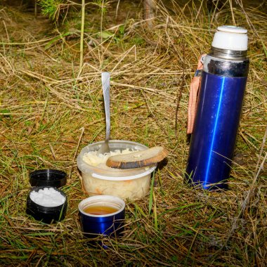 Kuru otların ve iğnelerin arka planında atıştırmalık erzaklar sunuluyor. Buna lahana ile birlikte bir fincan ekmeğin içinde sıcak bir içecek ve küçük bir kap tuz da dahil.