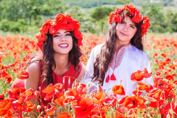 Two girls in a field of poppy flowers — Stockfoto