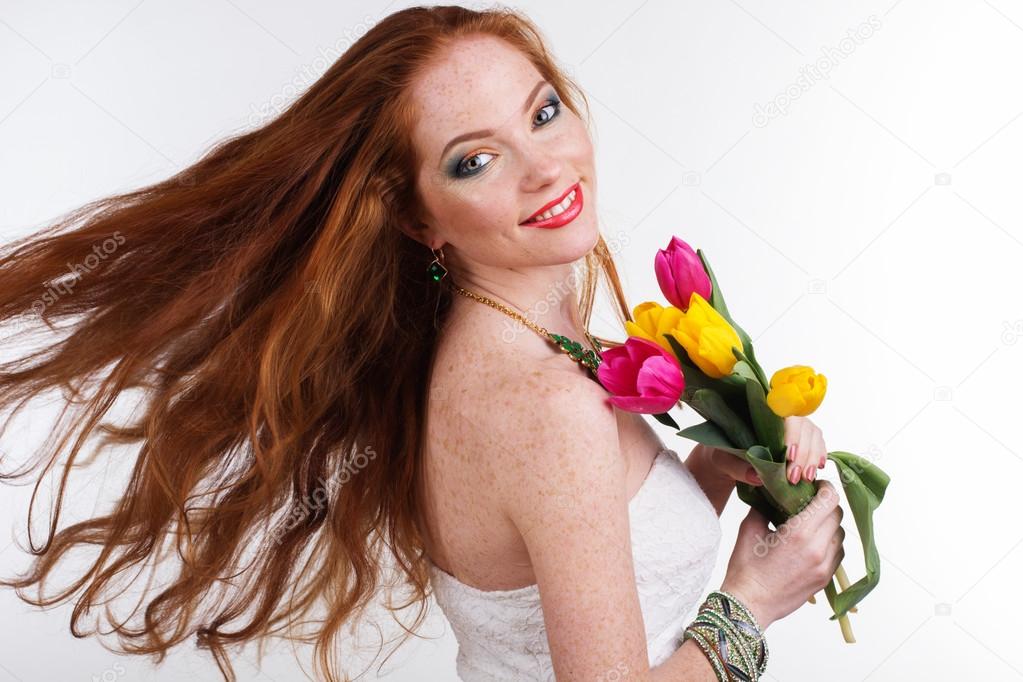 Girl with flying hair is holding bouquet of tulips