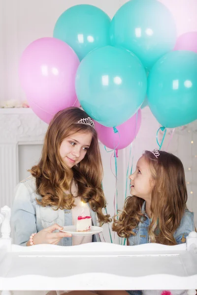 Two pretty sisters with birthday cake and balloons — Stock Photo, Image